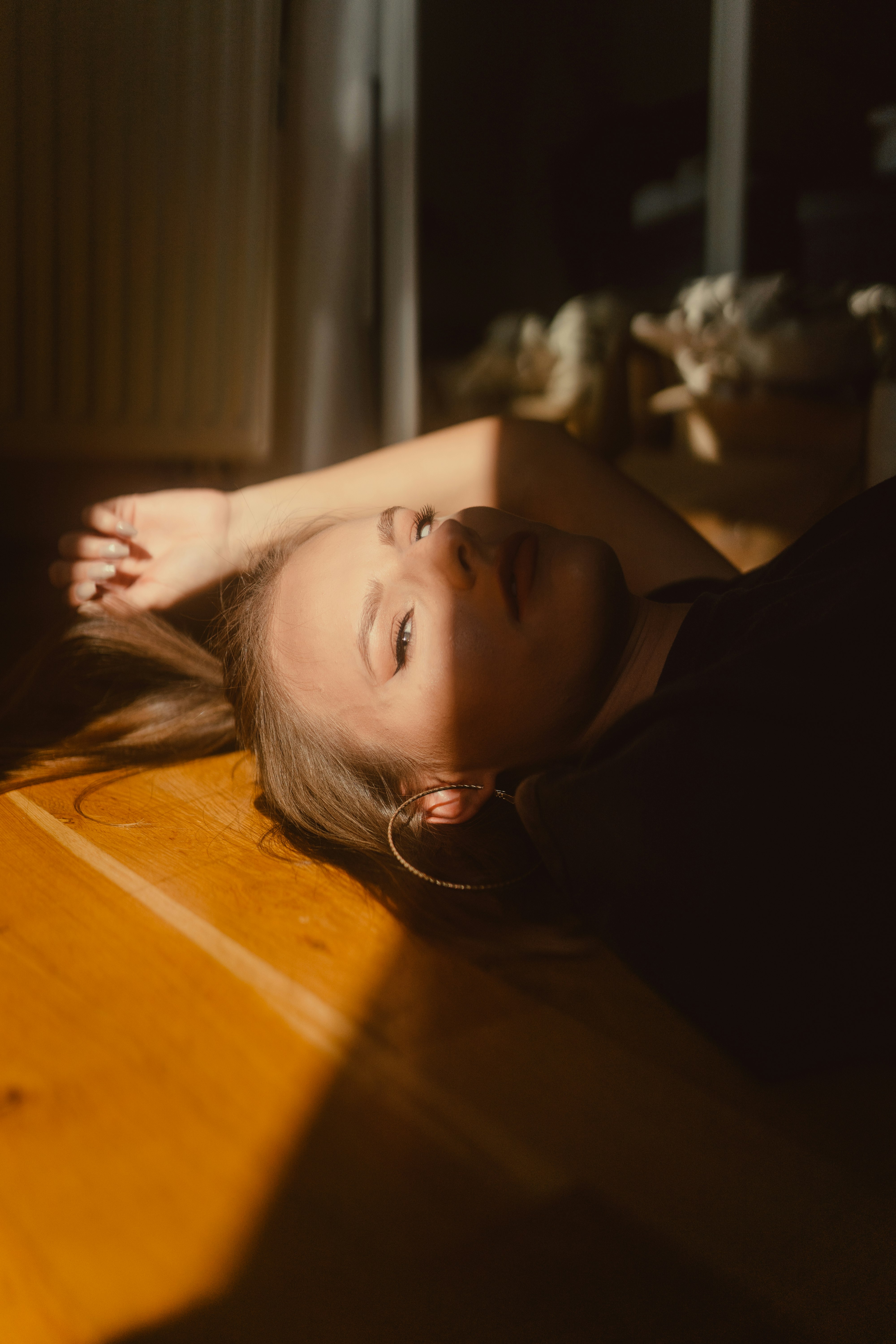 woman in black shirt lying on brown wooden floor
